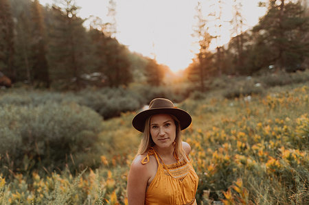 Mid adult woman in felt hat amongst wildflowers at sunset in rural valley, portrait, Mineral King, California, USA Stock Photo - Premium Royalty-Free, Code: 614-09270488
