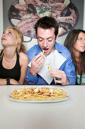 Man eating french fries Stock Photo - Premium Royalty-Free, Code: 614-00653788