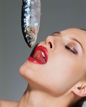 female tongue licking - Woman dangling fish towards her mouth Stock Photo - Premium Royalty-Free, Code: 614-00683990