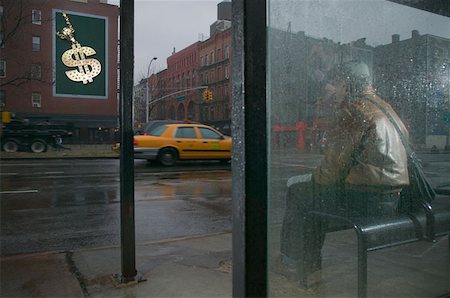 rain shelter - Man looking at billboard from bus shelter Stock Photo - Premium Royalty-Free, Code: 614-00966451