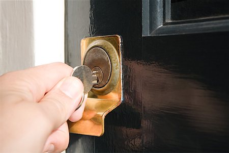 Person putting key in keyhole Stock Photo - Premium Royalty-Free, Code: 614-01219498