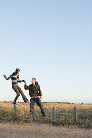 A young man helping a woman balancing on a fence Stock Photo - Premium Royalty-Free, Code: 614-02049786