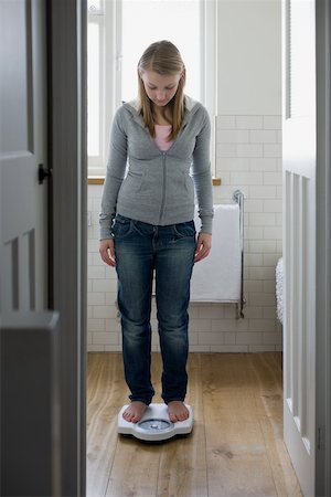 A teenage girl weighing herself Stock Photo - Premium Royalty-Free, Code: 614-02244112