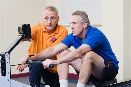 senior men at the gym - Personal trainer helping a man on a rowing machine Stock Photo - Premium Royalty-Free, Code: 614-02614027