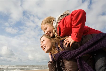 daughter piggyback at beach - Mother and daughter by the sea Stock Photo - Premium Royalty-Free, Code: 614-02680526