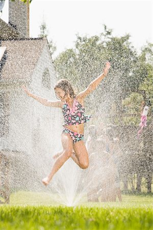 summer backyard party - Girl jumping in sprinkler Stock Photo - Premium Royalty-Free, Code: 614-03019967