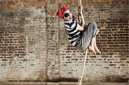 Young girl dressed up as pirate, climbing rope Stock Photo - Premium Royalty-Free, Code: 614-03469509