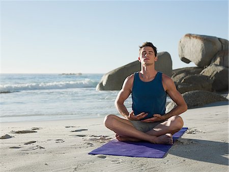 Young man doing yoga on beach Stock Photo - Premium Royalty-Free, Code: 614-03507092