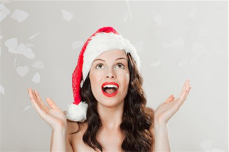 santa claus hat - Young brunette woman wearing Santa hat with confetti Stock Photo - Premium Royalty-Free, Code: 614-03507545