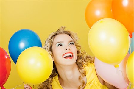 Young blonde woman with balloons against yellow background Stock Photo - Premium Royalty-Free, Code: 614-03507602