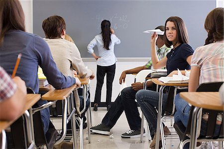 Female student with paper aeroplane in classroom Stock Photo - Premium Royalty-Free, Code: 614-03551975