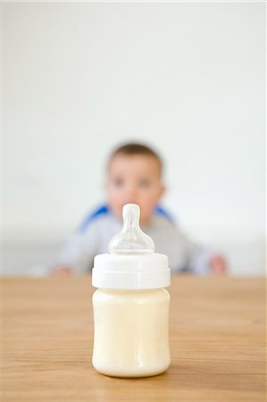 Baby bottle in foreground and baby in background Stock Photo - Premium Royalty-Free, Code: 614-03577005