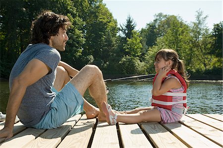 Father and daughter on jetty in lake Stock Photo - Premium Royalty-Free, Code: 614-03697050