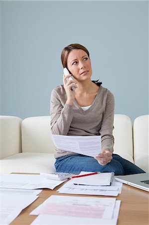 Young woman on the phone with paperwork Stock Photo - Premium Royalty-Free, Code: 614-03697170