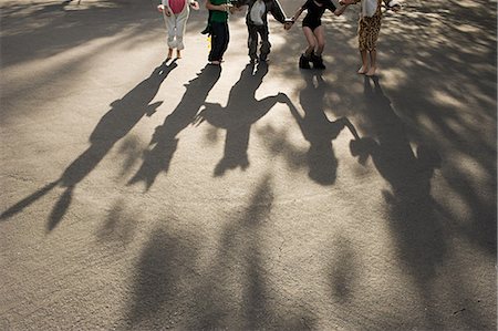Five children in fancy dress holding hands, casting shadow Stock Photo - Premium Royalty-Free, Code: 614-03747782