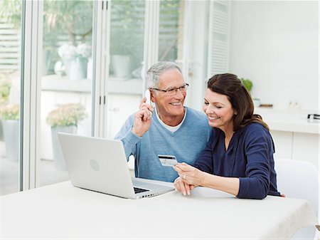 Mature couple using laptop, man on telephone Stock Photo - Premium Royalty-Free, Code: 614-03763794
