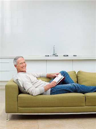 Senior man sitting on sofa reading book Stock Photo - Premium Royalty-Free, Code: 614-03763829