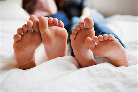 Two teenage girls lying on bed barefoot Foto de stock - Sin royalties Premium, Código: 614-03902811