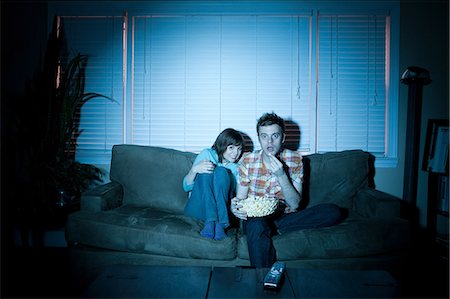 Young couple watching tv, man eating popcorn Foto de stock - Sin royalties Premium, Código: 614-03981527