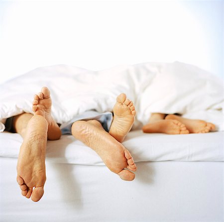 sleeping man foot - Pieds nus, qui sort d'une courtepointe sur un lit. Photographie de stock - Premium Libres de Droits, Code: 6102-03748629