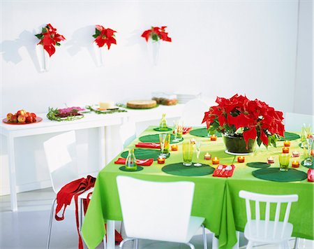 Elegant place setting on table with poinsettia flowers, Christmas feast in background Stock Photo - Premium Royalty-Free, Code: 6102-03858928