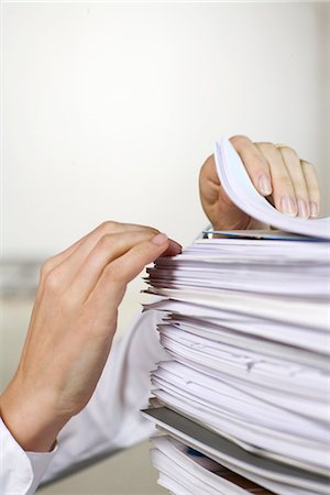 Two hands browsing through a pile of paper in an office. Stock Photo - Premium Royalty-Free, Code: 6102-03827263