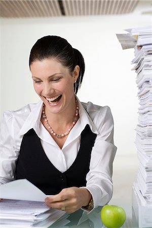 A smiling woman doing paperwork. Stock Photo - Premium Royalty-Free, Code: 6102-03827262