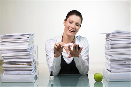 A woman in an office doing her nails. Stock Photo - Premium Royalty-Free, Code: 6102-03827268
