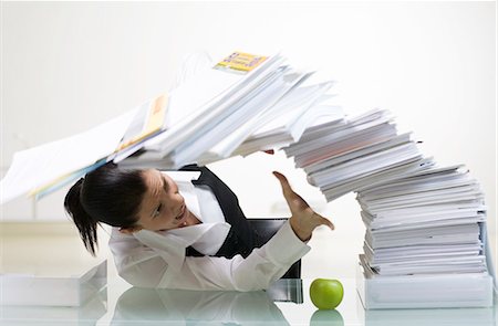 A woman in an office with a large pile of paper. Stock Photo - Premium Royalty-Free, Code: 6102-03827273