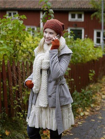 A woman standing by a red fence in the autumn, Sweden. Stock Photo - Premium Royalty-Free, Code: 6102-03904340