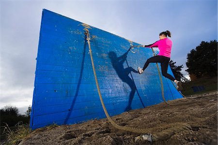 Woman climbing wall using rope in obstacle course Foto de stock - Sin royalties Premium, Código: 6102-03905979