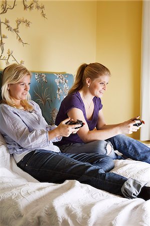 Two young women playing video game in bedroom Stock Photo - Premium Royalty-Free, Code: 6102-06025795