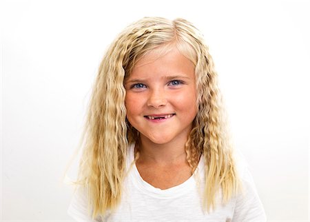 Portrait of smiling girl with missing front teeth, studio shot Stock Photo - Premium Royalty-Free, Code: 6102-06336539