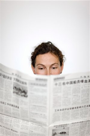 Close up of womans head behind newspaper Stock Photo - Premium Royalty-Free, Code: 6102-06336631