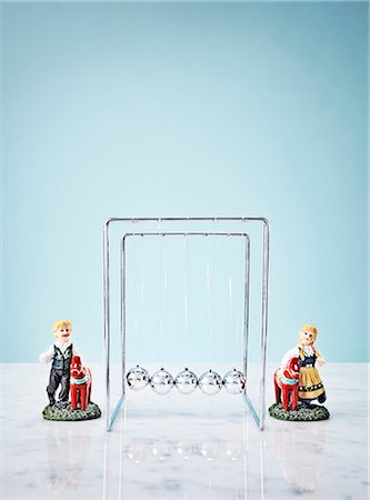 forked - Studio shot of Newtons Cradle and small figurines Stock Photo - Premium Royalty-Free, Code: 6102-06336805