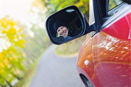 simsearch:6102-06026084,k - Woman smiling in rear view mirror on country road Stock Photo - Premium Royalty-Free, Code: 6102-06337048