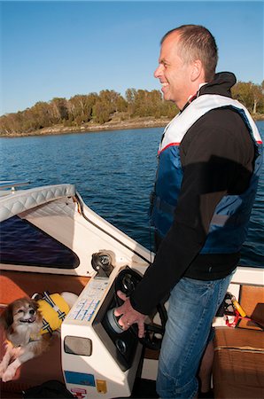 simsearch:6102-08001381,k - Smiling man with dog on boat, Ronneby, Blekinge, Sweden Stock Photo - Premium Royalty-Free, Code: 6102-07282622