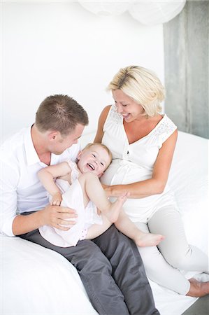 simsearch:6102-08566788,k - Parents playing with daughter on bed, studio shot Stock Photo - Premium Royalty-Free, Code: 6102-07768629