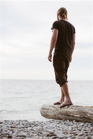 scandinavia - Man standing on log on beach, Gotland, Sweden Stock Photo - Premium Royalty-Free, Code: 6102-07768895
