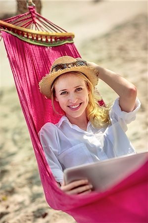 Portrait of young woman with laptop in hammock Stock Photo - Premium Royalty-Free, Code: 6102-07843896