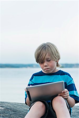 Boy using digital tablet at water Stock Photo - Premium Royalty-Free, Code: 6102-07844083