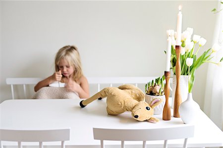 Plush toy, candles and flowers on table, girl on background Stock Photo - Premium Royalty-Free, Code: 6102-08000829