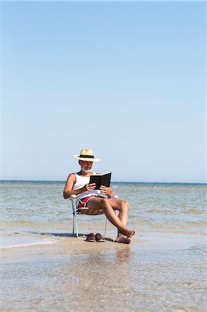 Mature man reading book on beach Photographie de stock - Premium Libres de Droits, Code: 6102-08000924