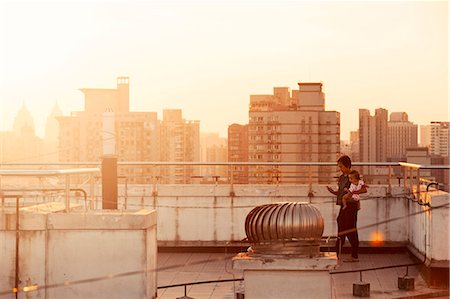 shanghai cityscape - Woman with baby on roof, cityscape at sunset on background Stock Photo - Premium Royalty-Free, Code: 6102-08001494