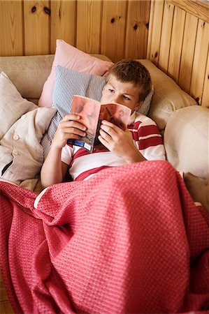 simsearch:6102-08168912,k - Boy reading book on sofa Photographie de stock - Premium Libres de Droits, Code: 6102-08120123