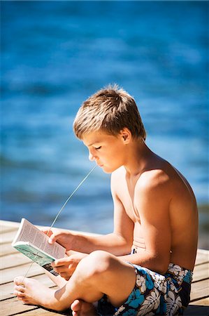 preteen boy shirtless - Boy reading book on jetty Stock Photo - Premium Royalty-Free, Code: 6102-08120130