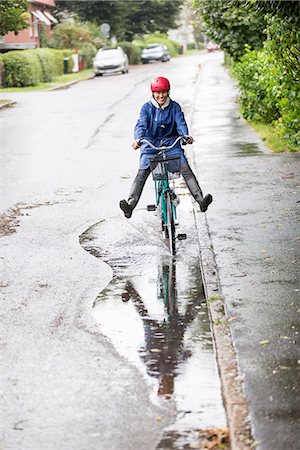 puddle in the rain - Woman riding bicycle through puddle Stock Photo - Premium Royalty-Free, Code: 6102-08388189