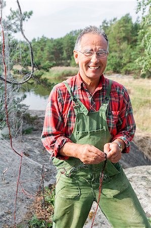 simsearch:6102-07158265,k - Smiling senior man repairing fishing net Stock Photo - Premium Royalty-Free, Code: 6102-08388419