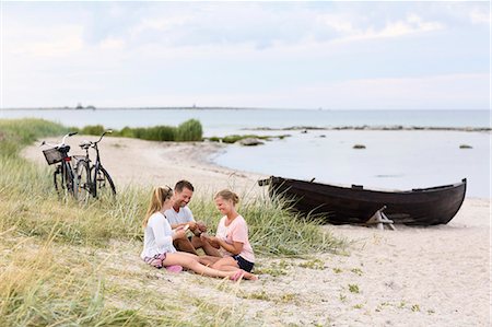 family on bikes - Family playing cards on beach Stock Photo - Premium Royalty-Free, Code: 6102-08481159