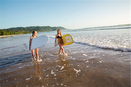 simsearch:6102-08542382,k - Two young women with surfboards wading in water Stock Photo - Premium Royalty-Free, Code: 6102-08542387